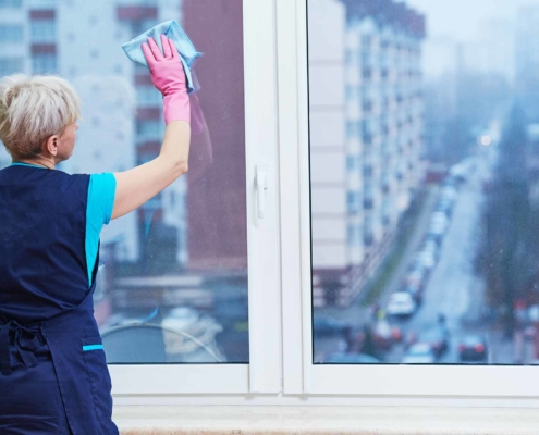 Cleaning worker using a rag to wipe down office windows