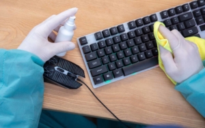 Cleaning worker using a spray to wipe down keyboard